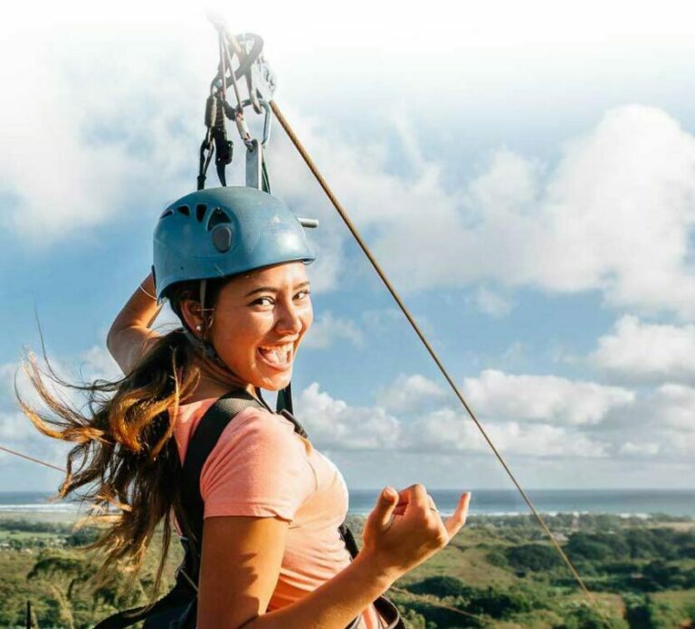 Woman give a shaka gestures while ziplining at CLIMB Works on the North shore, Oahu Zipline Tours.