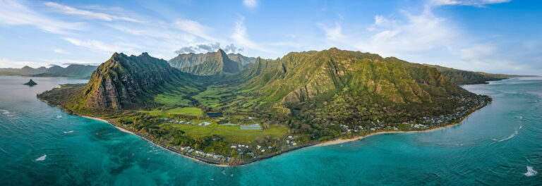 Aerial view of the Hawaiian island of Oahu. Lush green land surrounded by bright blue water.