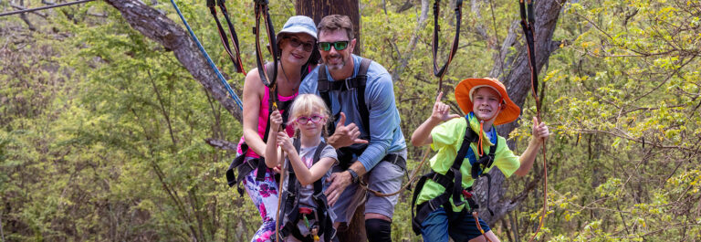 A family with a mom and dad and a boy and girl ziplining at Coral Crater Adventure Park in Oahu, Hawaii
