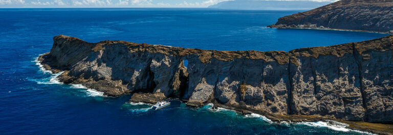 Aerial shot of cliffs of the Na Pali Coast in Kauai Hawaii surrounded by bright blue water