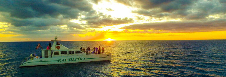 Tour Hawaii's sunset snorkel cruise boat on the ocean against bright yellow sunset
