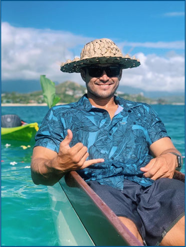 Man in straw hat relaxing in Tour Hawaii's boat in bright blue water