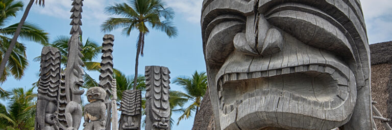 Tiki statues stand guard at the Place of Refuge on the Big Island Tour.
