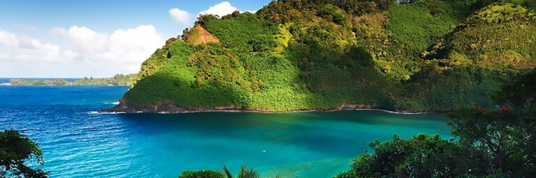 Turquoise blue water sits below a bend in the Road to Hana Tour.