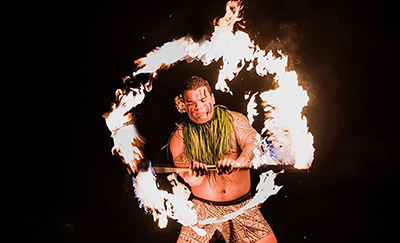 A luau dancer spins a flaming torch as part of the Fire Knife Dance.