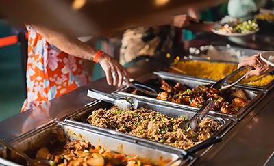 Guests select food from a Hawaiian Luau buffet.