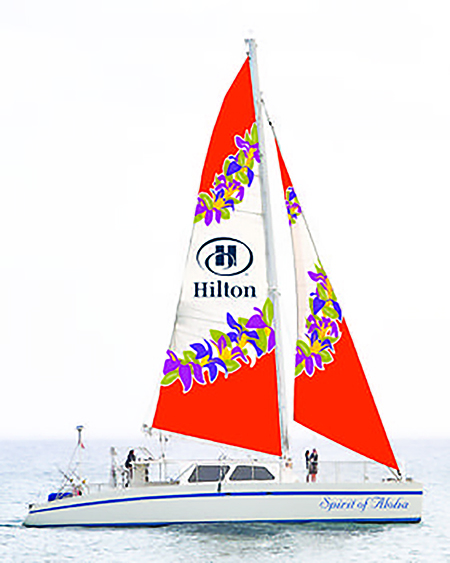 The Spirit of Aloha, a 65-foot sailing catamaran, with it's orange and white sails full of wind.