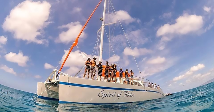 Guests stand on the bow of the Spirit of Aloha, a sailing catamaran in Waikiki.